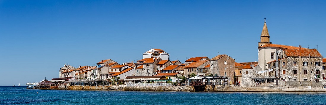 a coastal town with stone buildings and red clay tile roofs
