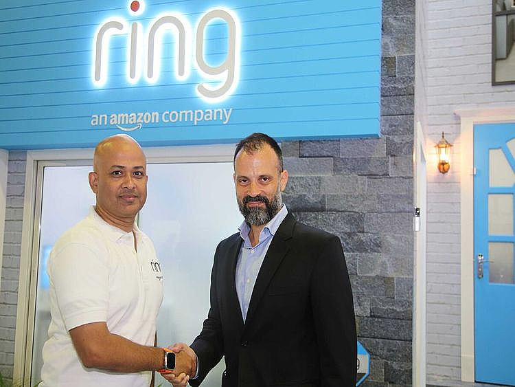 deux hommes se serrant la main lors d'une conférence sous un logo affichant le mot Ring