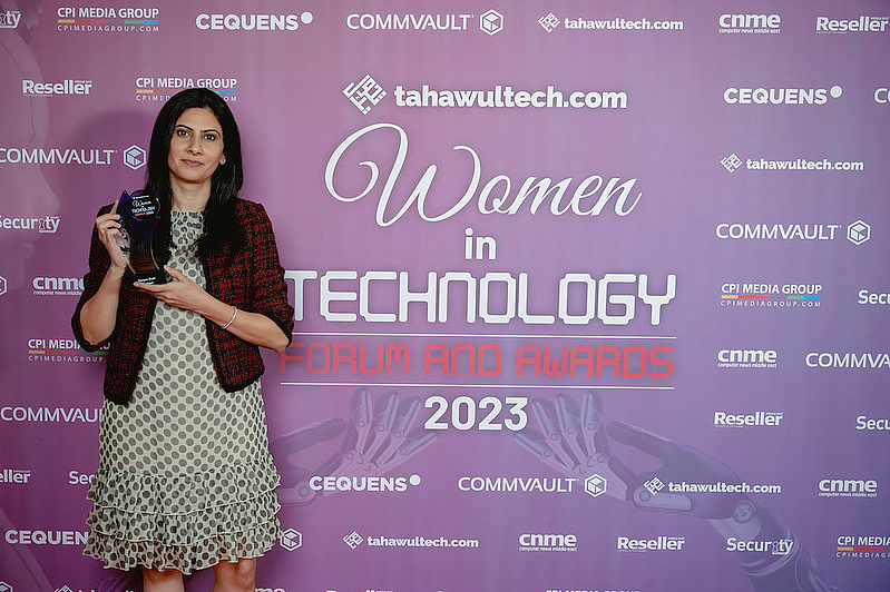 a woman holds a trophy in front of a presentation background. 