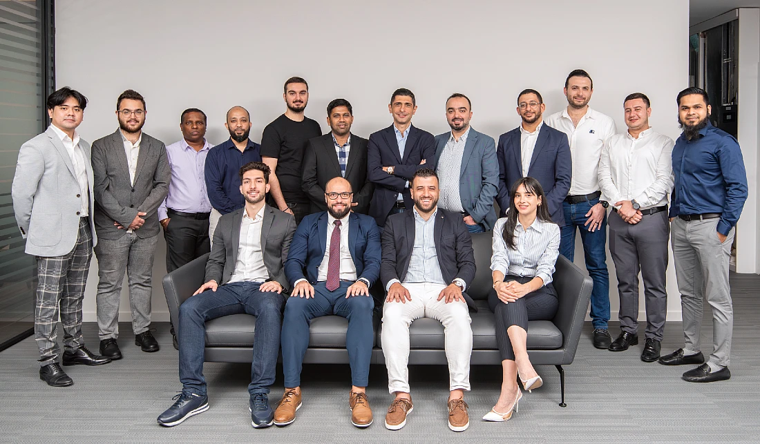 sixteen people in a group photograph. Four are seated at the front of the group.