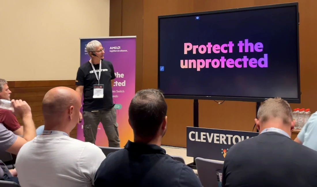 a man is presenting to a group of people with a screen behind him with the words protect the unprotected on it