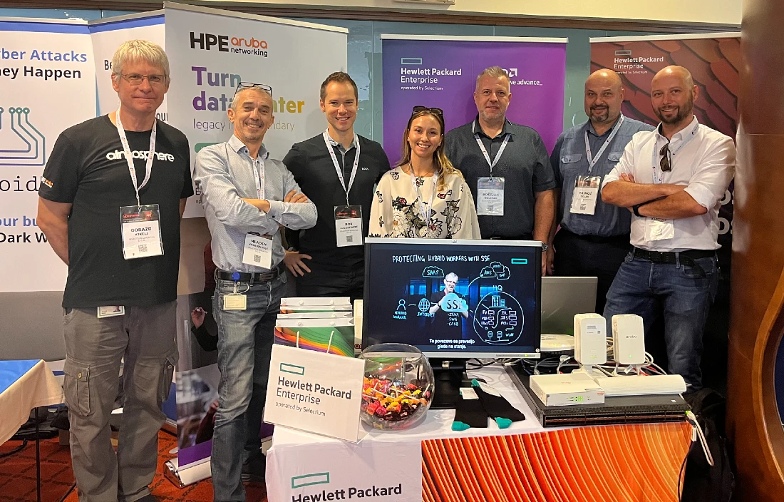 Seven people stand at a hi tech conference exhibition stand. 