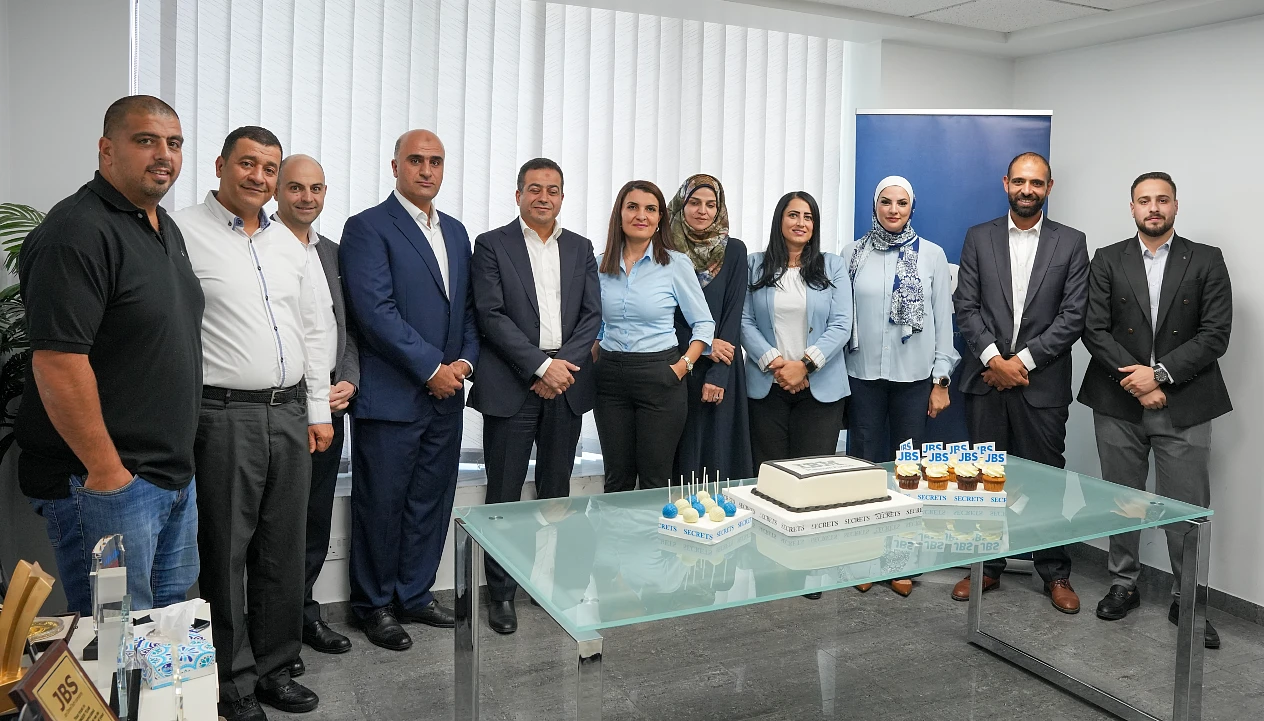 11 men and women are seen in a group photograph in an office setting