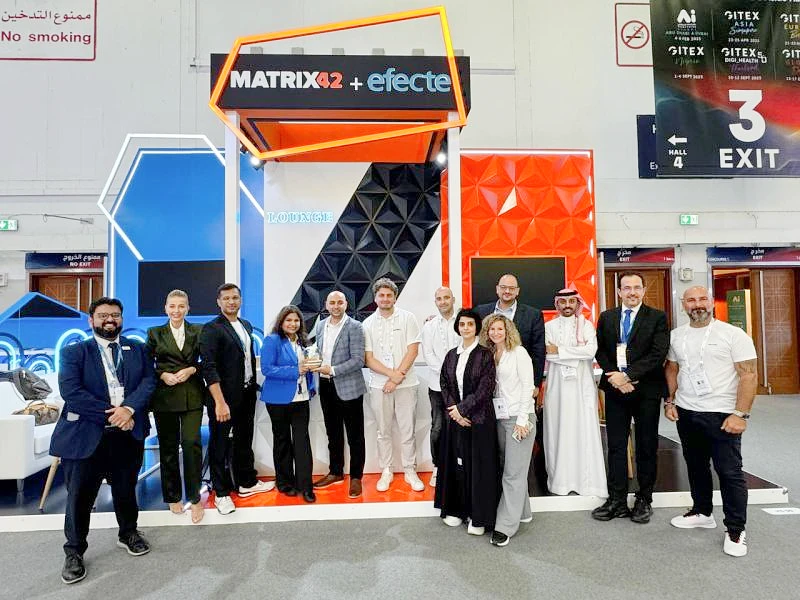 13 people seen at an exhibition stand as two people in the centre accept a trophy