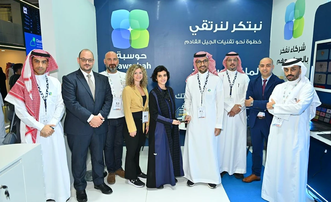 nine people are seen at a hi-tech exhibition stand accepting a trophy