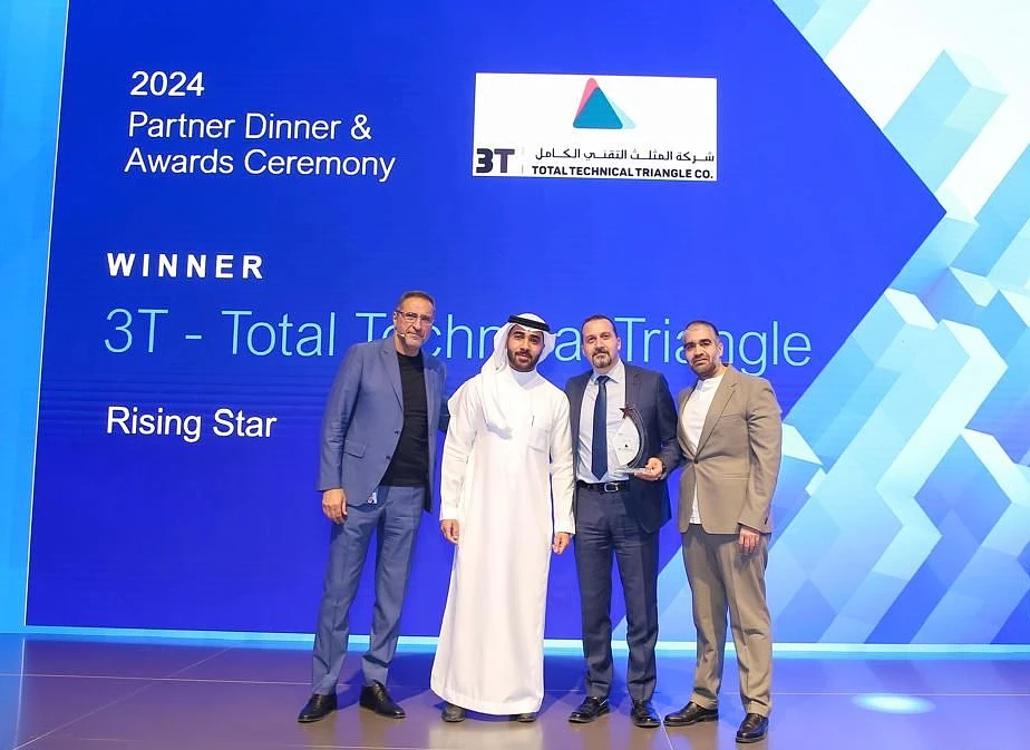 Four men are seen on a presentation stage holding a trophy