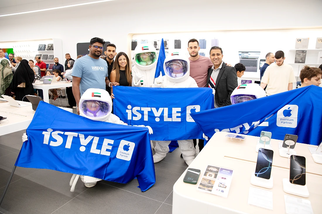 des personnes sont vues regroupées autour de drapeaux bleus sur lesquels est écrit le mot iSTYLE. Parmi elles, des personnes vêtues de costumes d'astronautes.