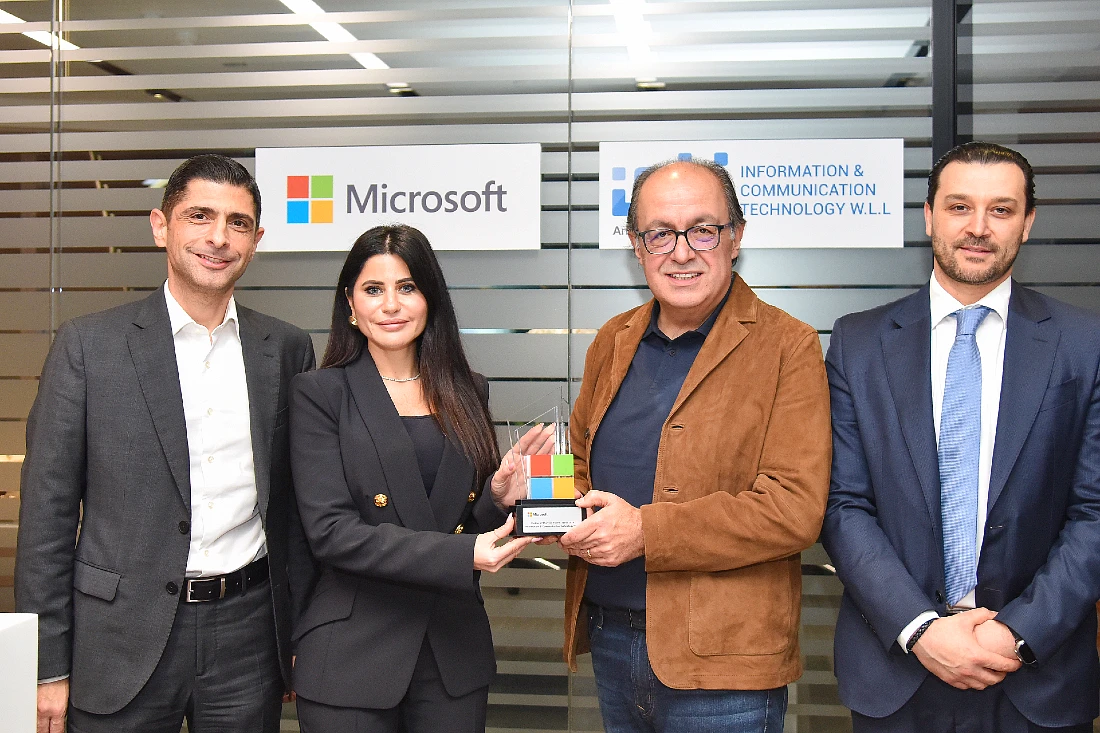 four people in a group photo with a trophy being handed over