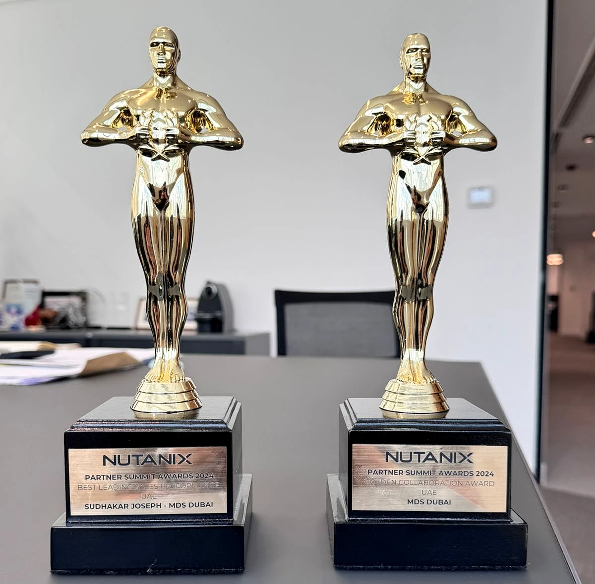 Two gold-colored engraved trophies side by side