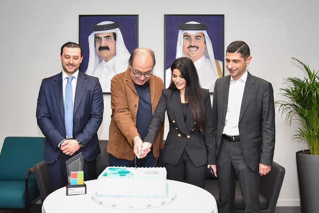 four people in a group photo as two of them cut a celebration cake