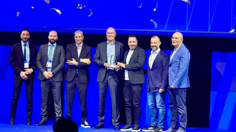 seven people on a presentation stage as an award is handed over