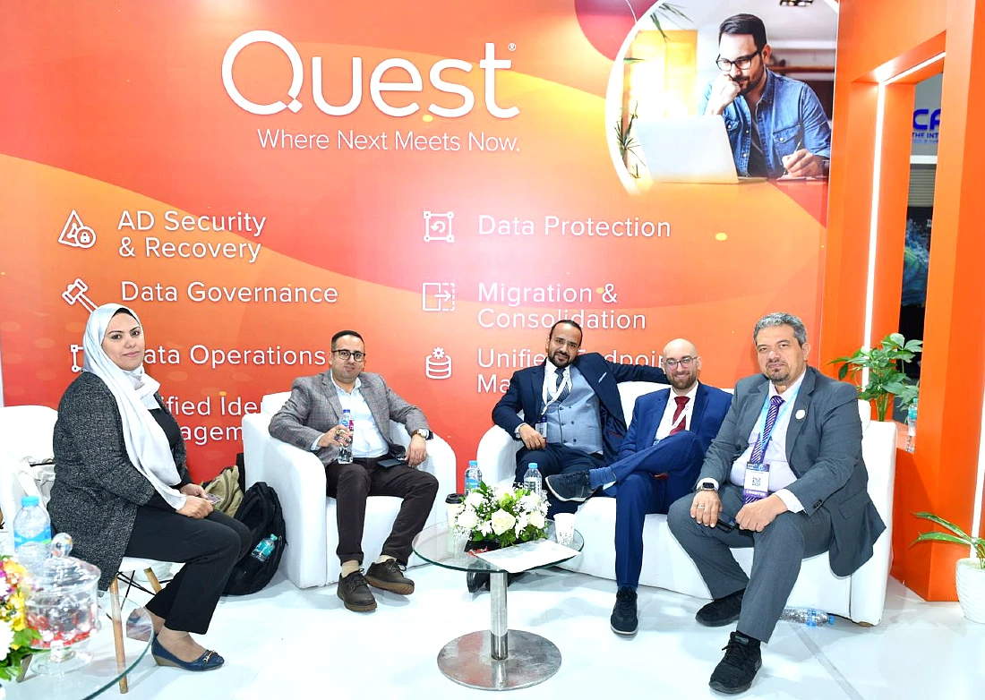 five people sit in a group photo at an exhibition stand