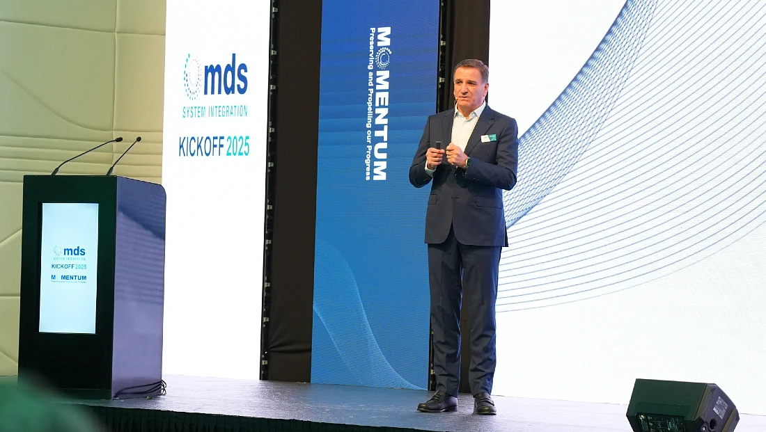 a man in seen presenting on stage in front of a blue and white backdrop 