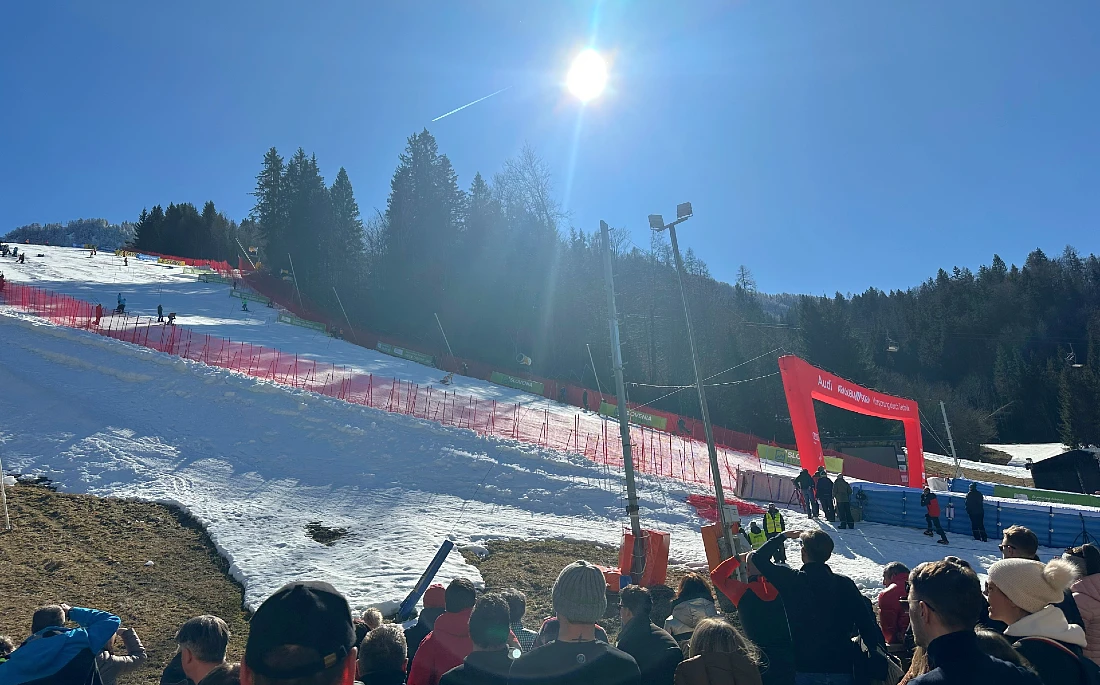 view of a ski slope with a blue sky and the sun prominent